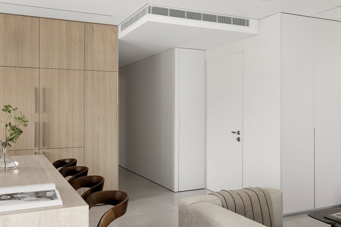 Detalle de la isla, las banquetas y el mobiliario blanco del living
